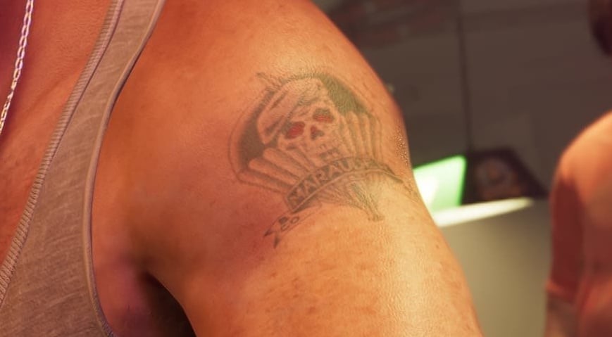 Faded tattoo on Jason's shoulder: a skull wearing a beret with red eyes over an open parachute, with a banner reading MARAUDER